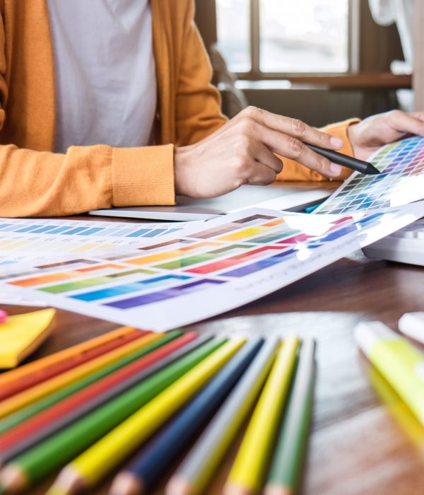 Image of female creative graphic designer working on color selection and drawing on graphics tablet at workplace with work tools and accessories.